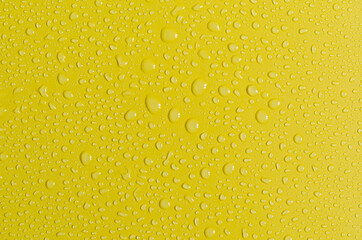 Bright yellow background with large and small water drops. Texture of a water drop top view.