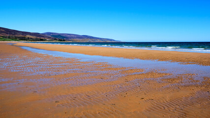 Brora beach on a sunny day with clear blue skies looking north towards Kintradwell and Glen Loth