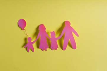Bright red human figures on a yellow background. The concept of family relations. Cardboard figures of adults and children close-up