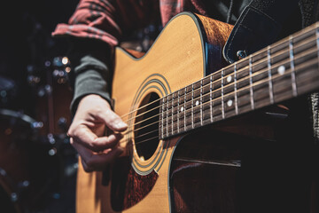 Obraz na płótnie Canvas Guitarist playing acoustic guitar in the dark close up.