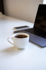 Close up of a coffee cup in the workplace near a laptop.