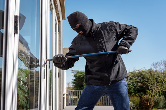 Burglar breaking into a house via a window with a crowbar