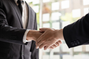 Two businessmen are shaking hand in the office room.