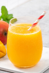 Fresh beautiful delicious mango juice smoothie in a glass cup on gray table background.