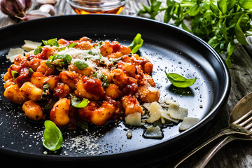 Gnocchi with in tomato sauce, parmesan and basil on wooden table
