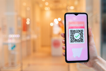 A female's hand holds a smartphone with a promo code for a discount in the internet store. Close-up. The concept of online shopping and discounts