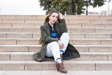 Portrait of a beautiful and pensive hippie girl who sits on the steps