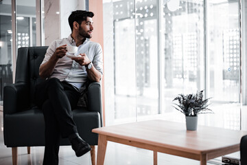 Portrait of handsome man drinking coffee at hotel lobby.