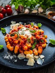 Gnocchi with in tomato sauce, parmesan and basil on wooden table
