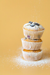 Three muffins stapled with blueberriey and orange background. High quality photo