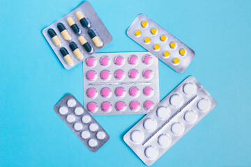 Blisters with pills, for health and protection. Yellow color with green capsules, white, sealed in silver packages on a blue background. Slimming, anti-aging or anti-virus products. Contraceptive