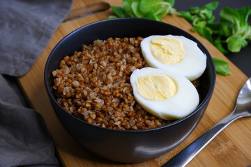 Buckwheat porridge with egg on a black background. Tasty food. Cooking.