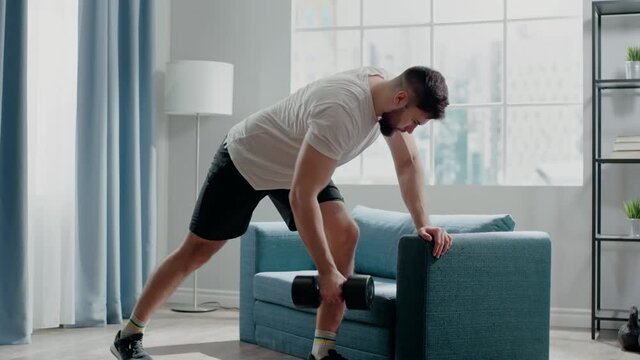 Bodybuilder practices bent-over row holding dumbbell