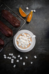 Traditional French eclairs with orange slices on a dark grey background .