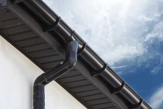 View of brown roof with gutter drain and blue sky.