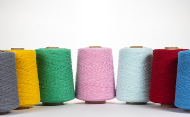 Large multi-colored bobbins with thread on a white background. Space for text