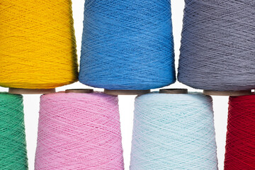 Evenly arranged colorful bobbins in three rows. Close-up. Manufacturing, textiles, cotton, layout