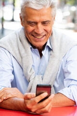 Obraz premium Close up older man looking at mobile phone in hand