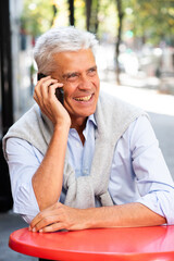 older gray hair man talking with mobile phone in city