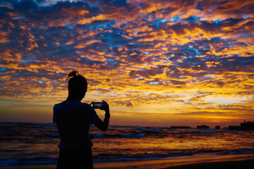 Back view of millennial woman shooting video vlog about getaway vacations using mobile application for photographing, female blogger connecting to 4g for clicking images and sharing to travel website
