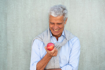 smiling older man looking at apple in hand