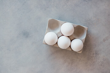 White eggs in a stand are on a gray concrete table. Cooking, food, ingredients