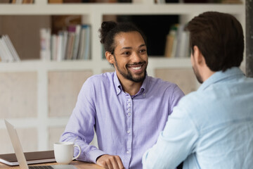 Close up smiling African American man with colleague working on project together, diverse coworkers...