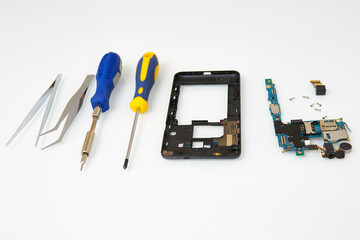 Disassembled smartphone and tools for its repair: tweezers and screwdrivers. The process describing the repair of a smartphone