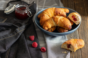 Freshly baked sweet homemade rolls filled with jam sprinkled with castor sugar, served on a rustic...