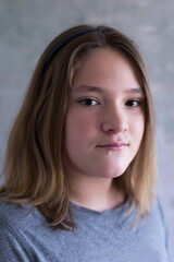 Fototapeta premium Closeup of pre-teen girl in grey top looking ahead with small mysterious smile