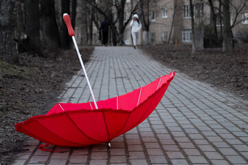 the red umbrella is lying on the street on the stone pavement on a spring autumn summer cloudy day upside down upside down