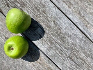 Two green apples on a gray wooden background. Copy space. View from above. Place for your text. Diagonal orientation of the wood strips.