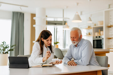 Doctor visiting senior patient at home, talking about medication.