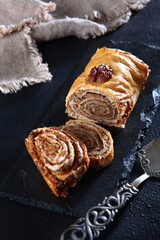 Roll with walnuts and honey. Fresh baked goods. Vertical photo.Black background. Vintage dessert spatula