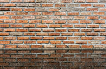Old brick wall background with water reflection on terrazzo tile floor.