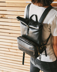 Laptop leather backpack Mens roll top backpack. Hipster wears a trendy black backpack. Back view.