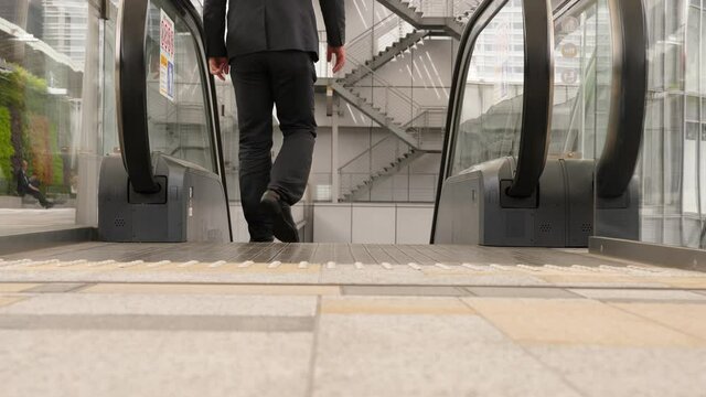 Man walk down on escalator, low camera show trodden down shoes and legs. Everyday life, details of Tokyo city, casual wear of male citizens