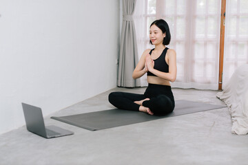 Obraz premium Asian young sporty slim woman coach internet video online training oga instructor modern laptop screen meditate relax breathe easy seat pose gym healthy lifestyle concept.