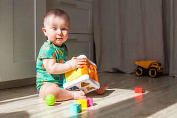 Eight-nine month baby boy plays on the floor