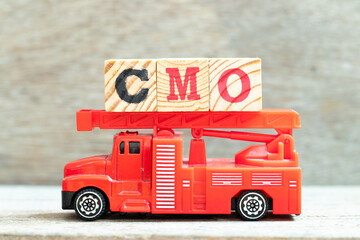 Fire ladder truck hold letter block in word CMO (Abbreviation of Chief Marketing Officer, Contract Manufacturing Organization) on wood background