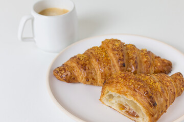 Plate with three tasty croissants on white background with cup of coffee. French food
