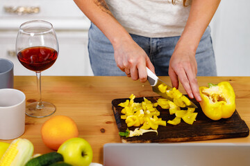 Hands of a woman cutting bell pepper on wooden cutting board