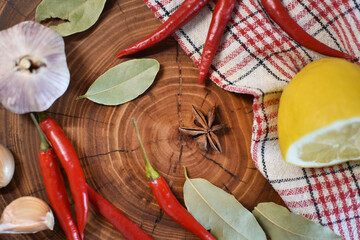 Hot chili peppers, lemon, garlic and spices on a wooden board
