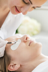 Obraz na płótnie Canvas Cosmetician giving eyelash treatment to customer