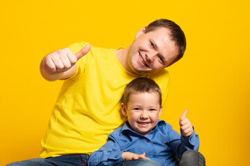 Happy father's day! Emotional dad and son hugging on yellow background.