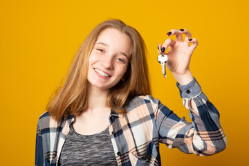 Young happy girl in casual clothes holds the car keys. Emotional teen girl was presented with the keys to the car.