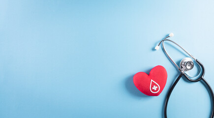 Medical and donor concepts. Doctor stethoscope and a handmade red heart with a sign or symbol of blood donation for world blood donor day on pastel blue background.