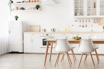 Minimalist design of kitchen. Dining table with white chairs and furniture with utensils, small white refrigerator near window