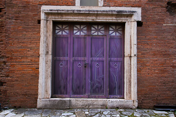 Purple wooden door, with ancient marble uprights, located at the Mercati Traianei in Rome