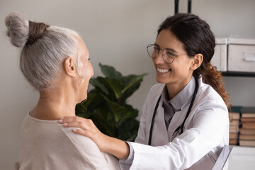 Supporting patient. Pleasant female doctor in glasses encourage unhealthy senior lady at...